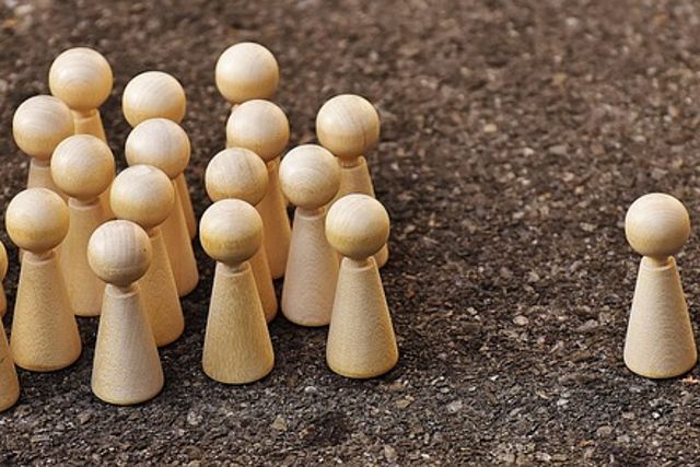 Holzfiguren als Gruppe, eine Figur steht etwas abseits
